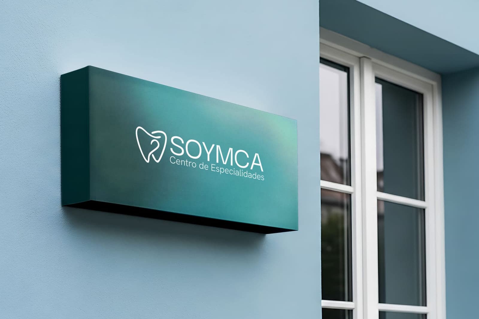 Rótulo luminoso de la clínica en la fachada, en verde azulado, con el logo del diente y «Soymca, Centro de Especialidades».